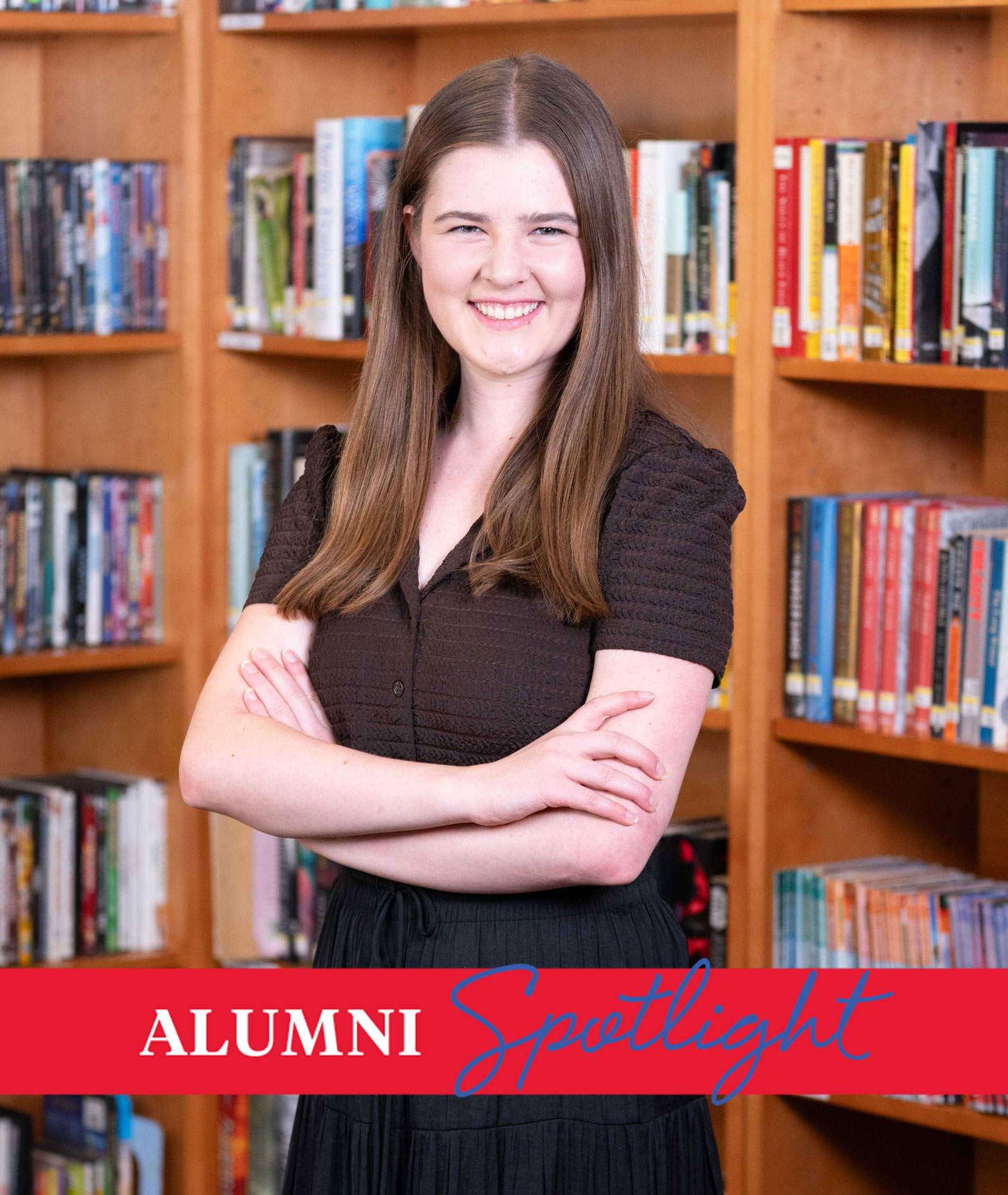 Dance alum Anna Kelley Zielke poses in a black shirt in front of bookcases