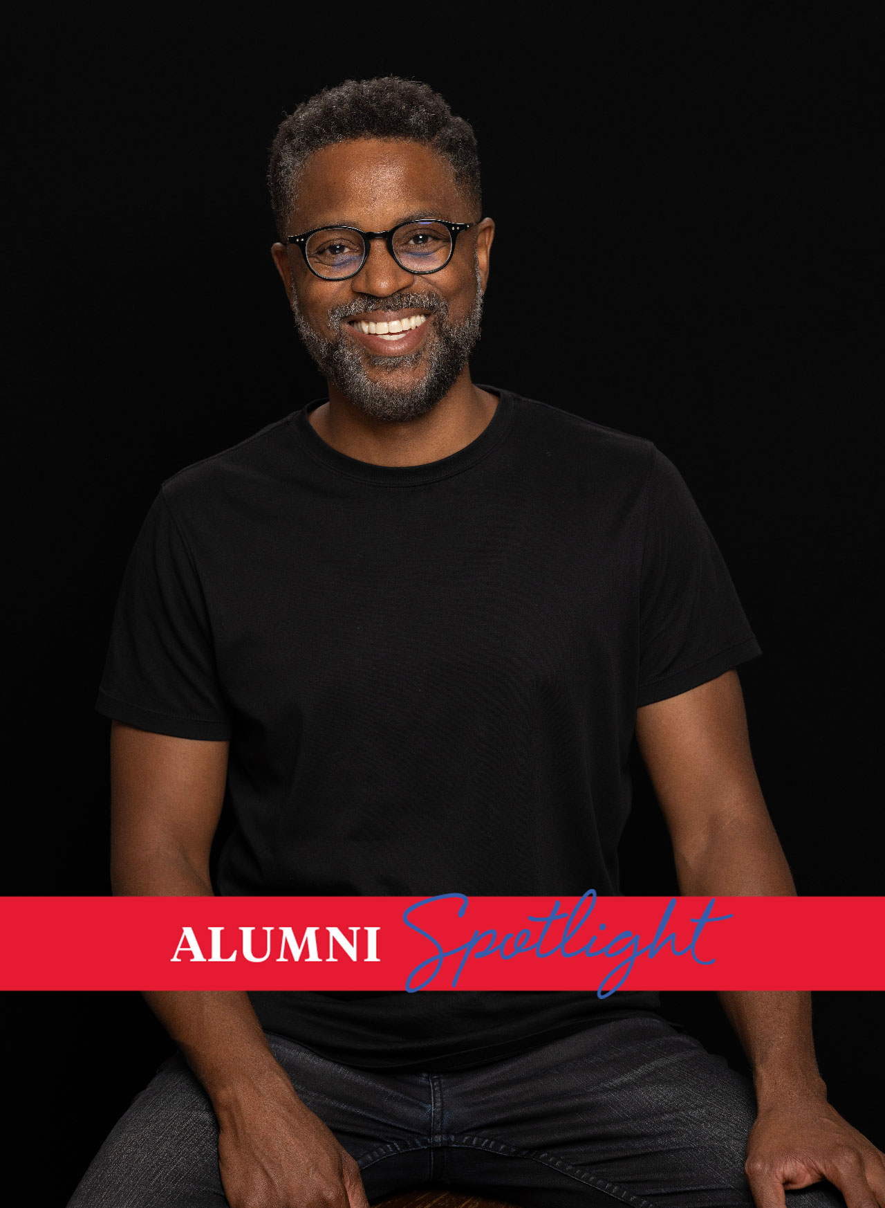 Music alum Neeki Bey poses in a black shirt against a black background.