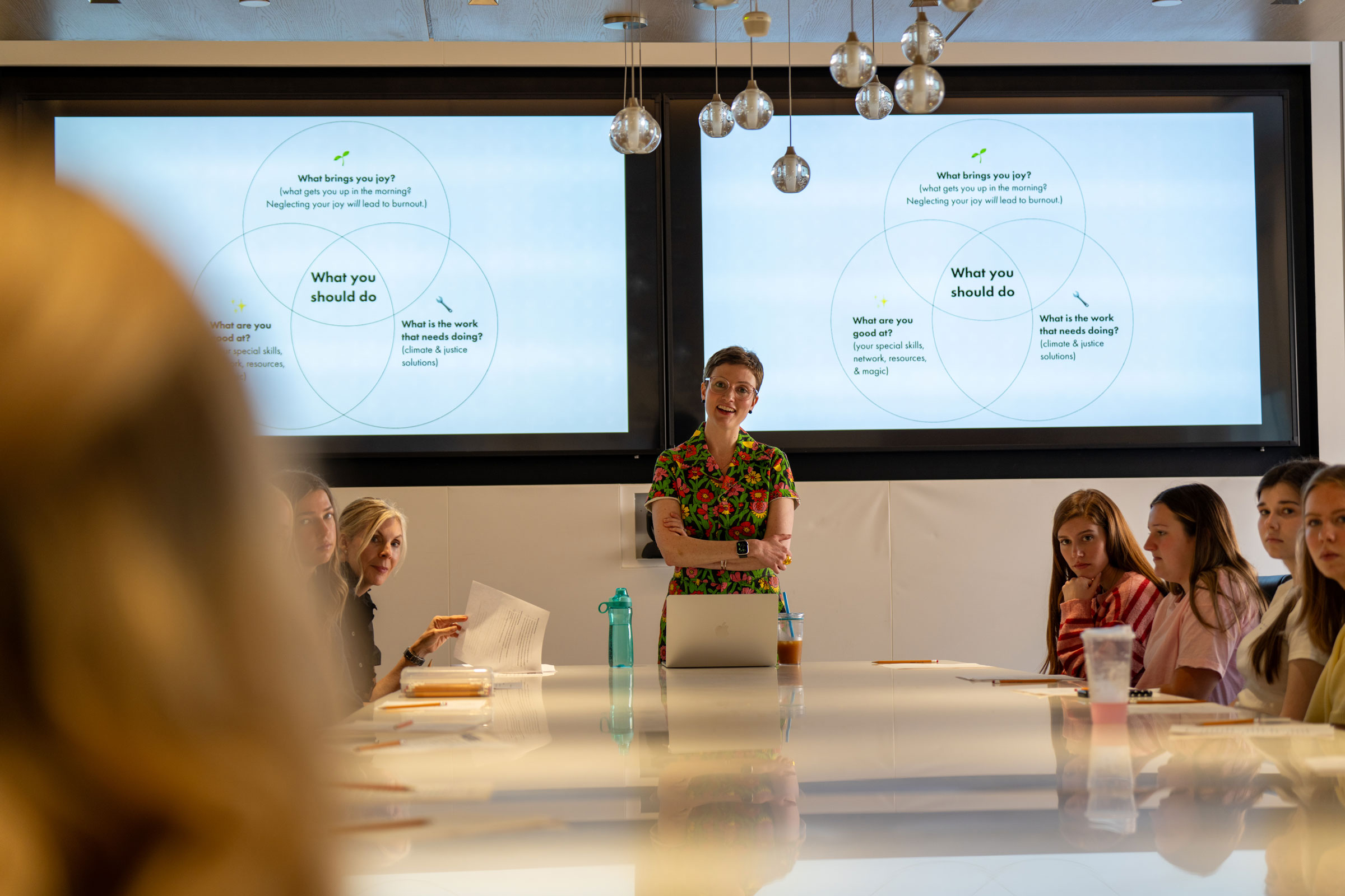 Professor Sara Idacavage stands in front of a powerpoint teaching a sustainability workshop.