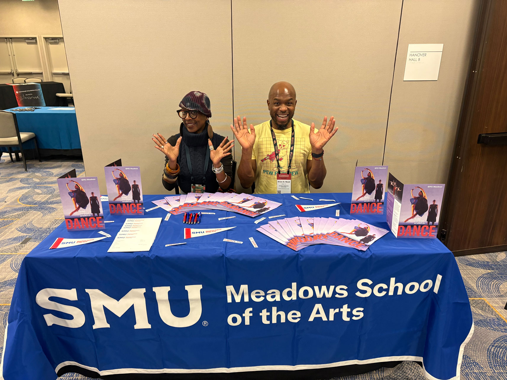 Professors Michelle N. Gibson and Alvon Reed pose at an SMU table with dance brochures