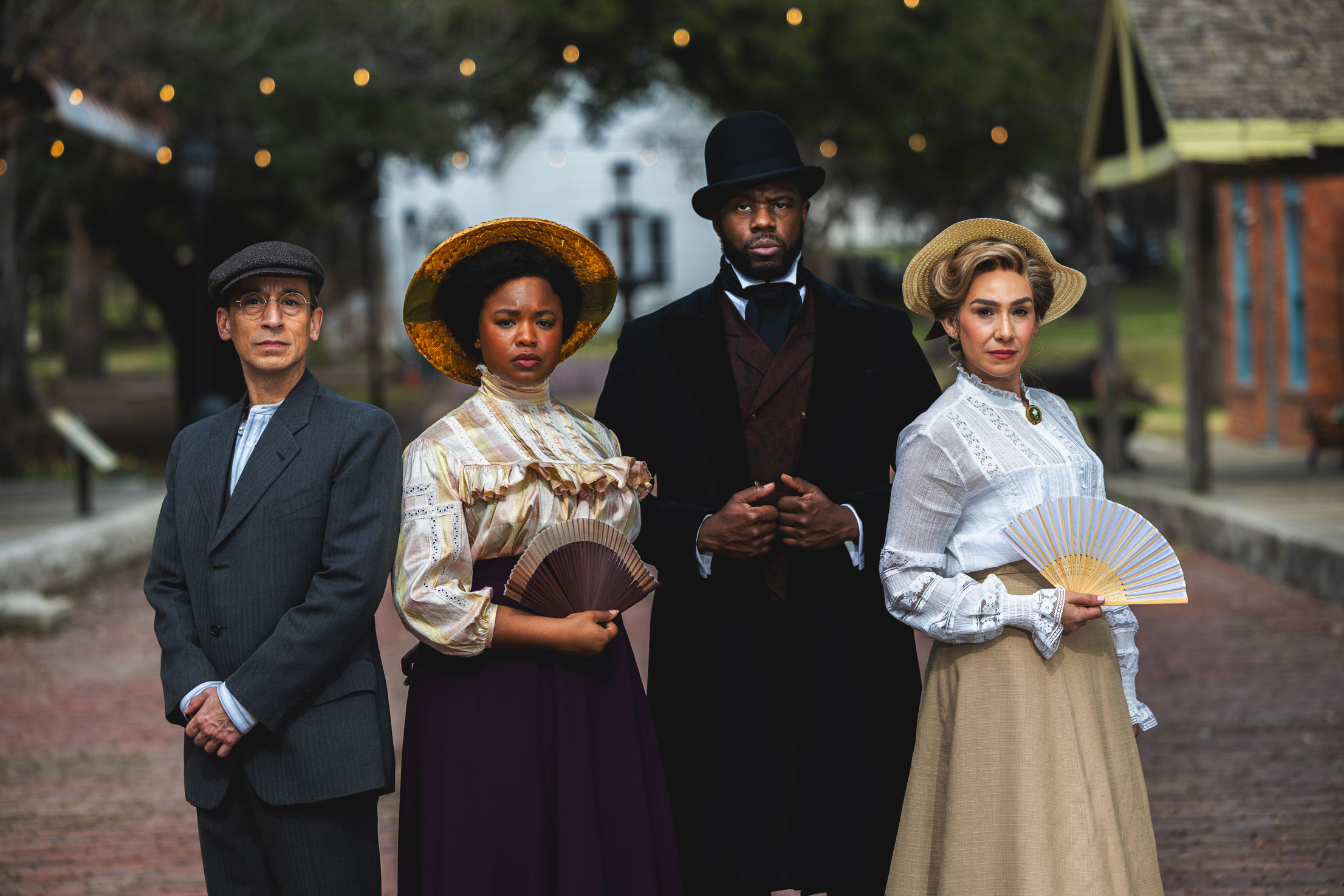 Four members of the cast of Ragtime stand in costume in the street