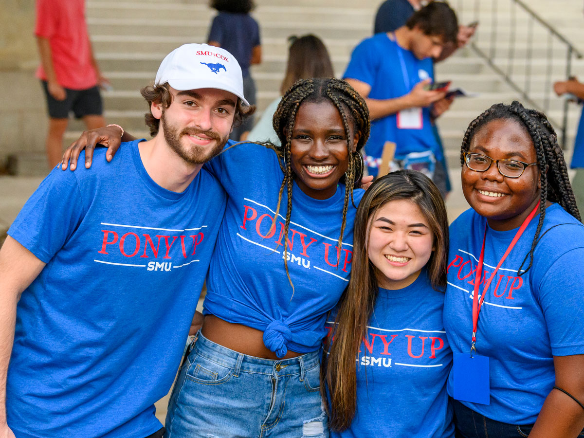 Group of students in blue SMU shirts hugging. 