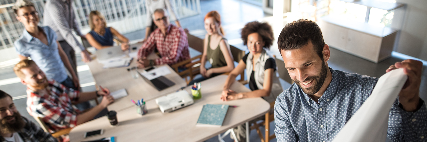 people meeting around a conference table while one writes on a white board