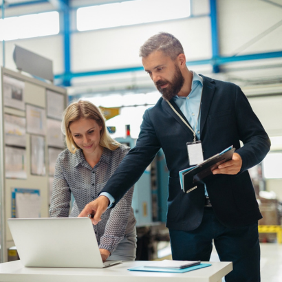 Two people looking at computers in a warehouse