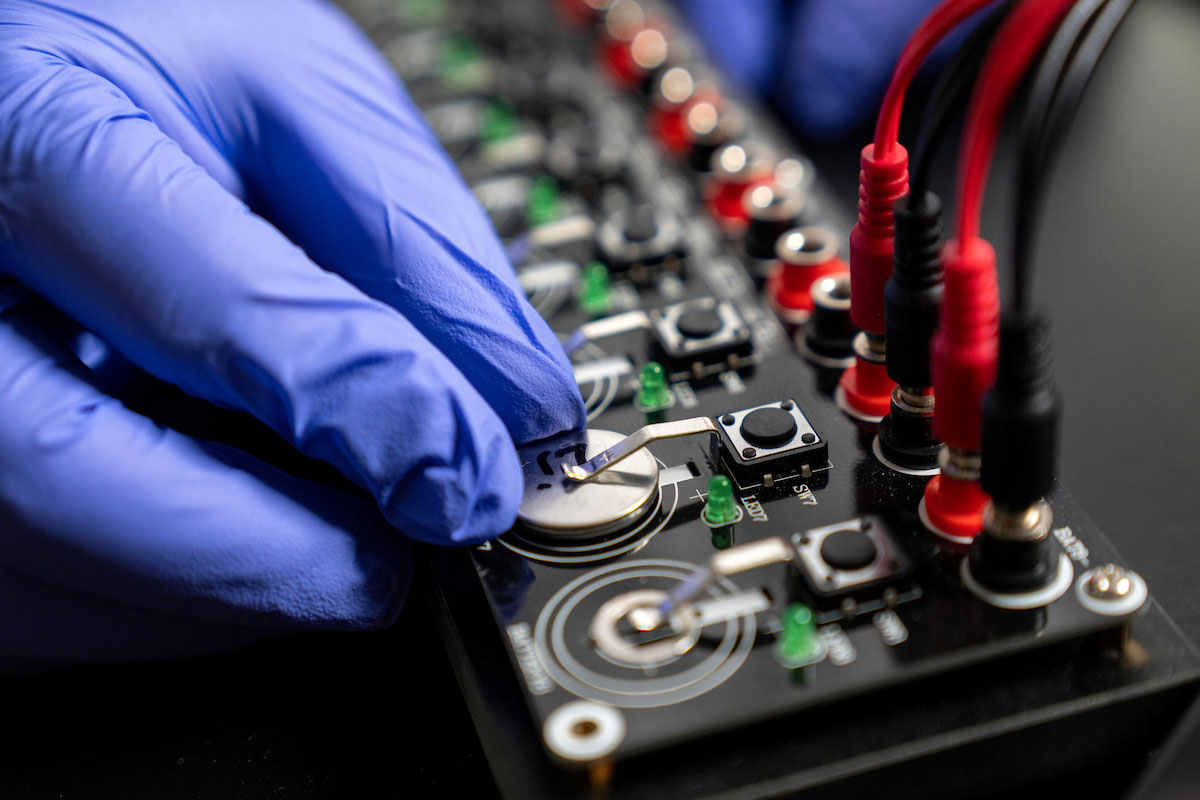 Researcher works with advanced battery and energy storage testing equipment in a laboratory environment.