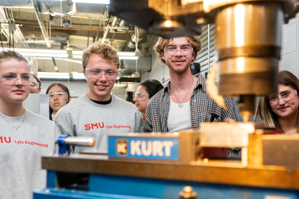 Group of engineering students observing a machine