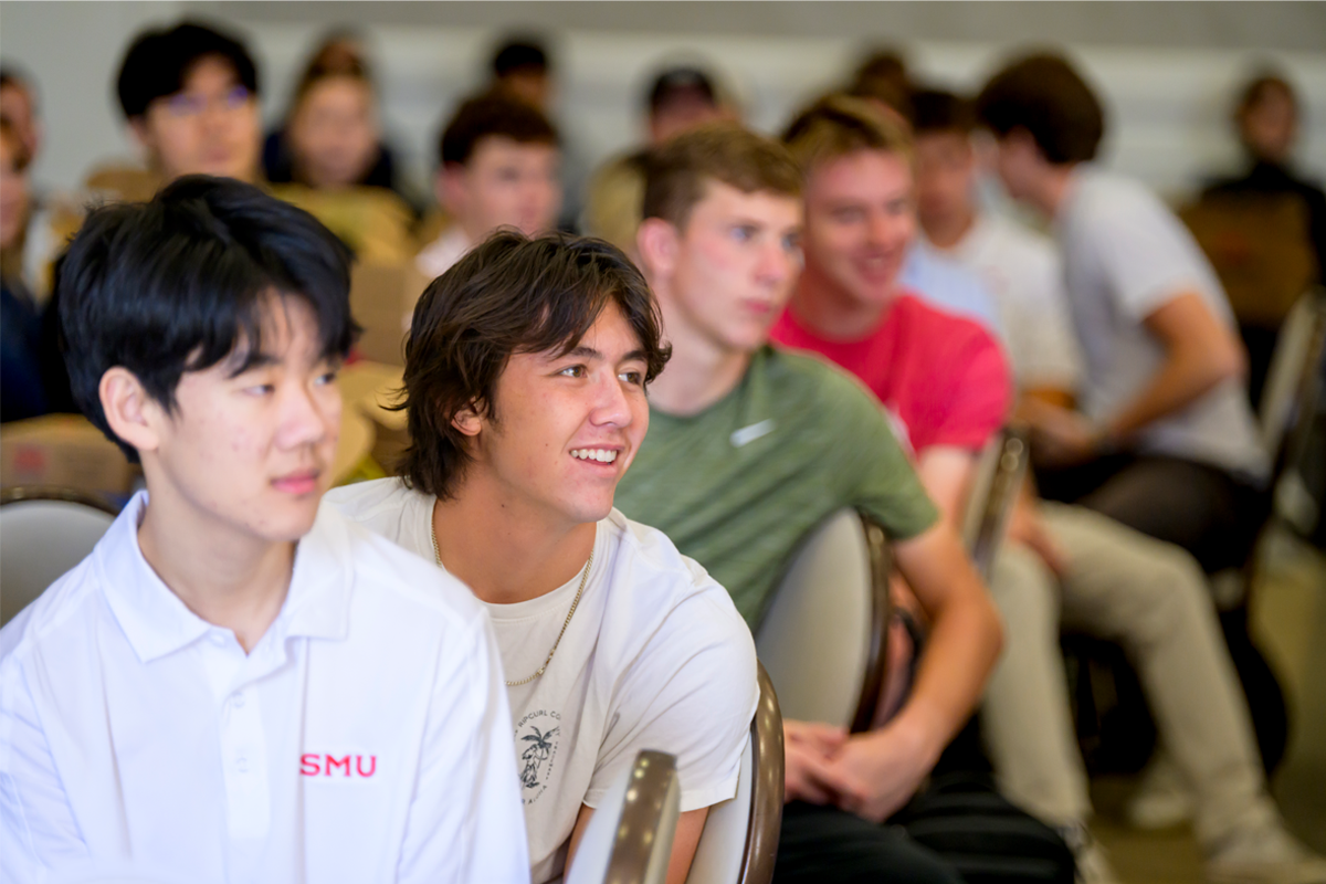 Students seated in rows (some blurred and some in focus), listening attentively and leaning forward from their chairs during a Hilltop Scholars Storytellers Collective lecture.