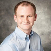 Kenny Martin is a white man with red hair in a buzzcut. He is wearing a light blue button-up.