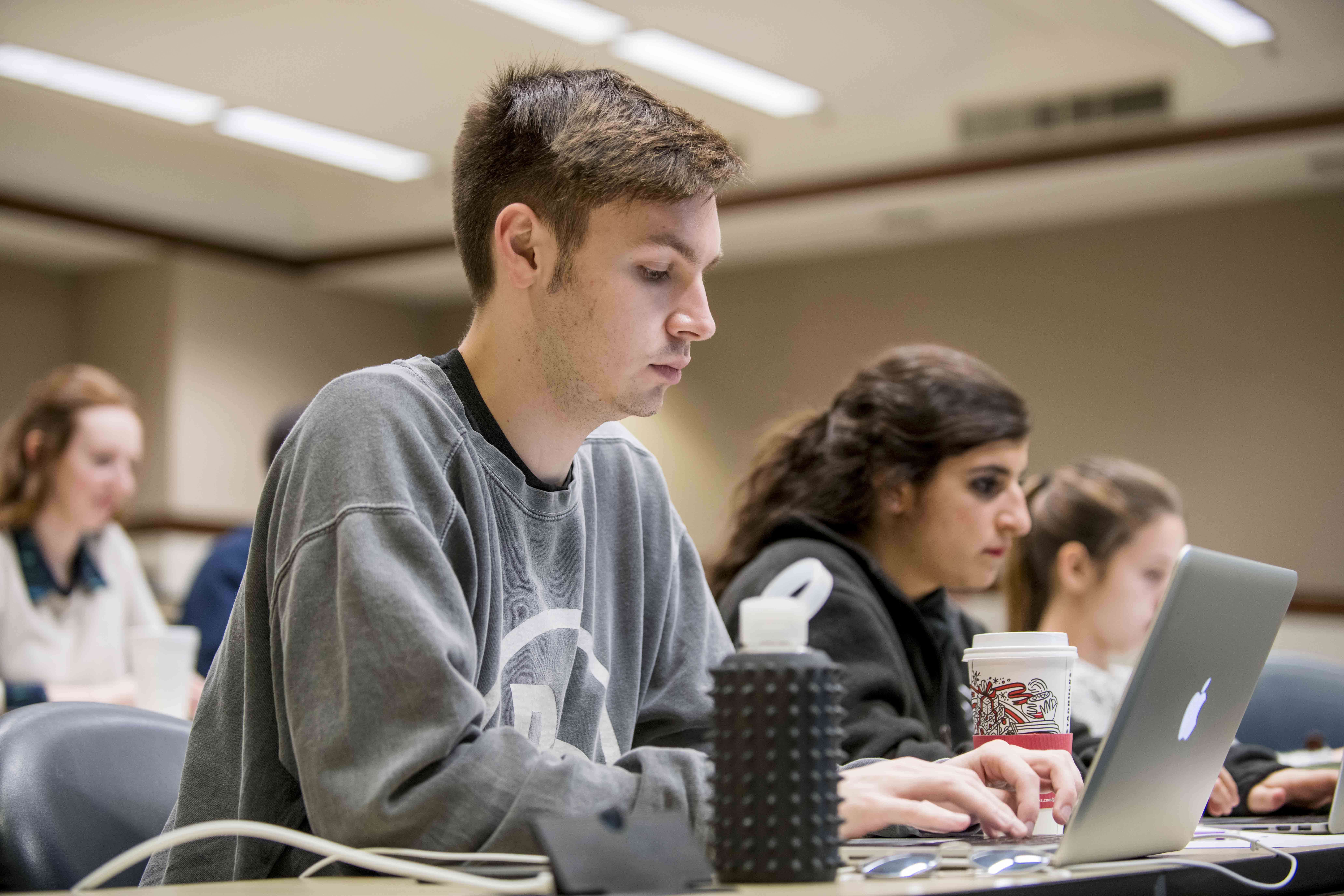 Students in class focus on their laptops