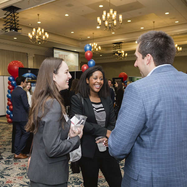 Photo of networking event with people talking and smiling
