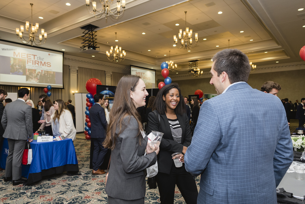 students speaking to a recruiter at a networking event