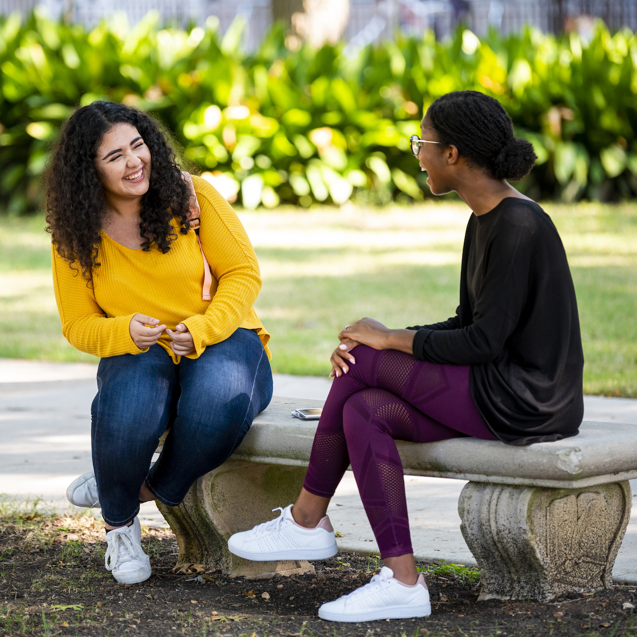 two students on a bench laughing