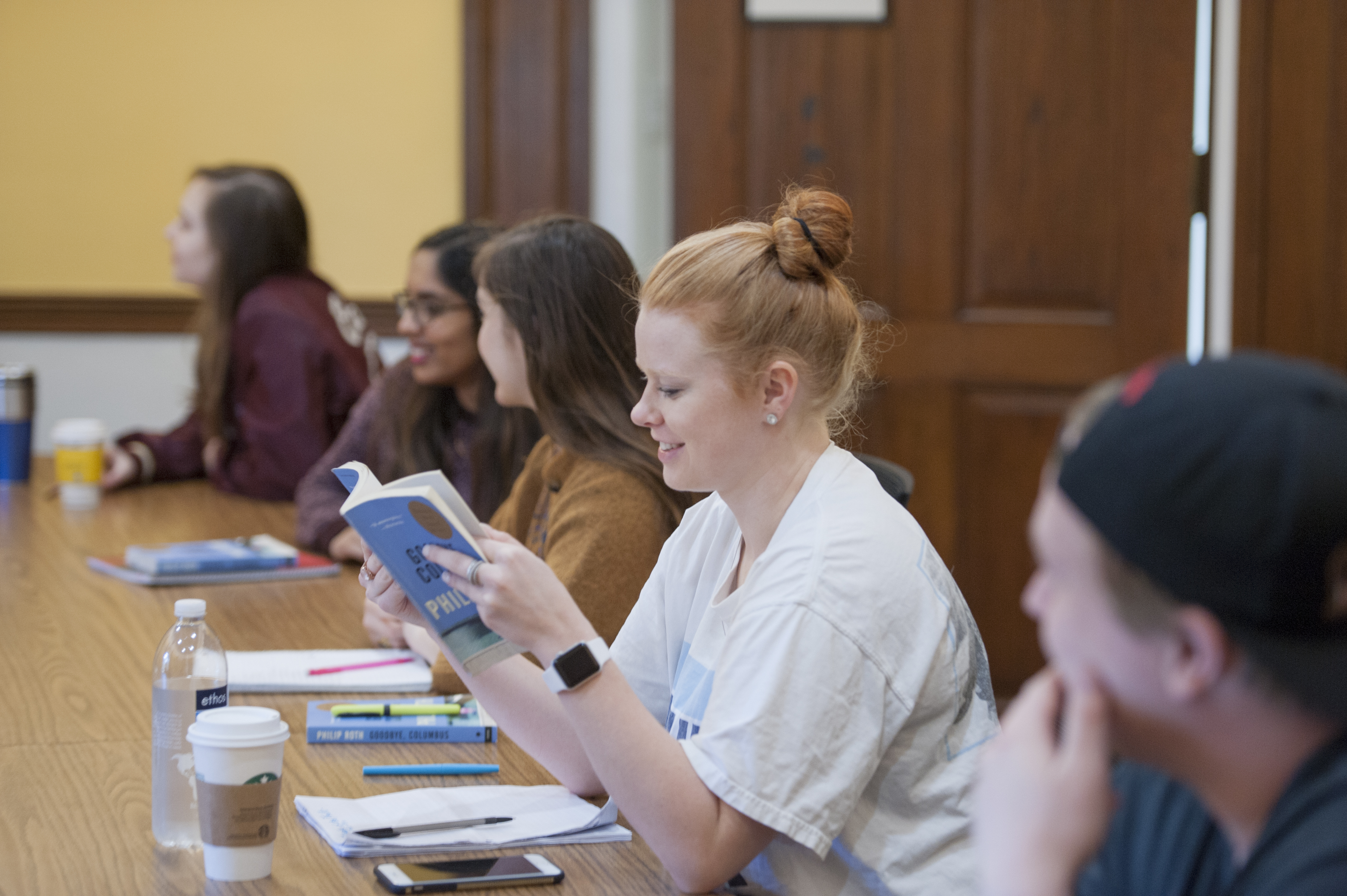 Students looking at assigned reading in English class