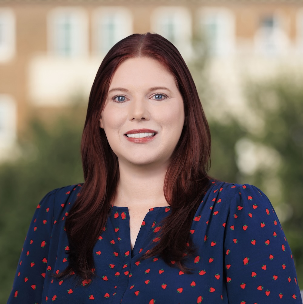 Headshot of Amanda Tolbert, Academic Advisor in the UAC. Amanda has red hair and a blue dress shirt with a red flower pattern.