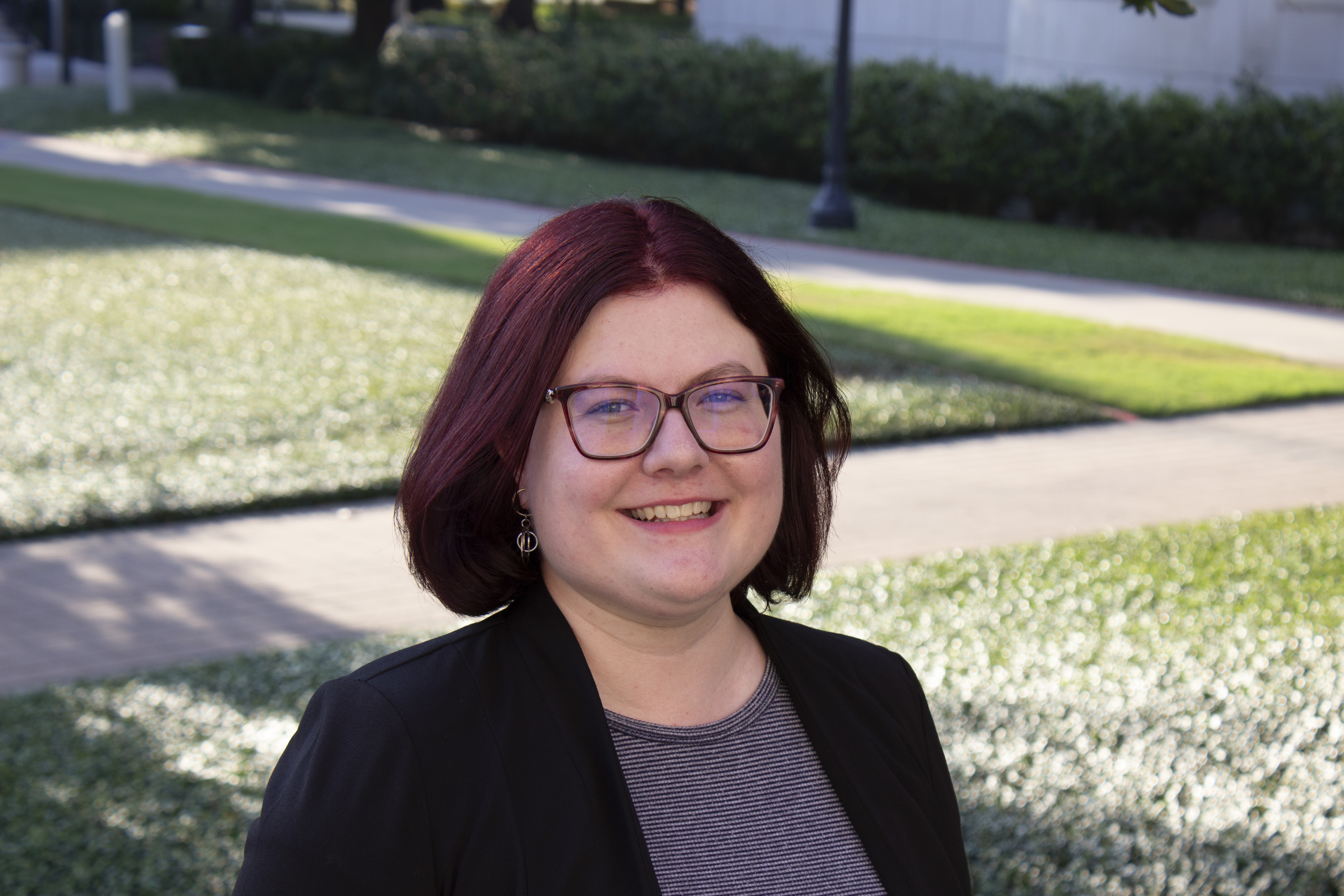 Headshot of Melissa Whitler, Academic Advisor in the University Advising Center. Background displays sidewalk and grass between the Blanton and Caruth buildings on SMU's campus.