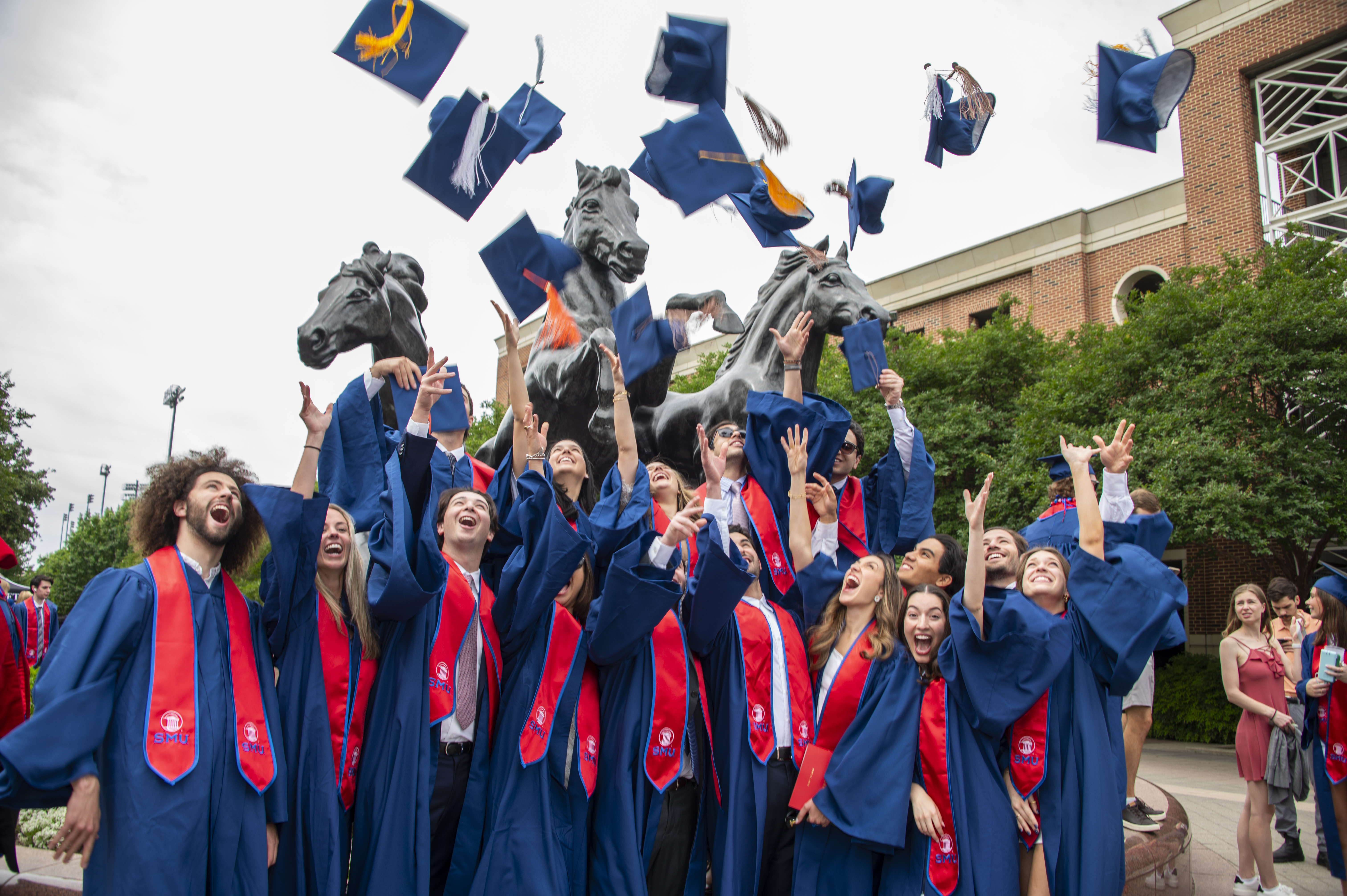 Students in graduation regalia throwing their mortar boards up in celebration