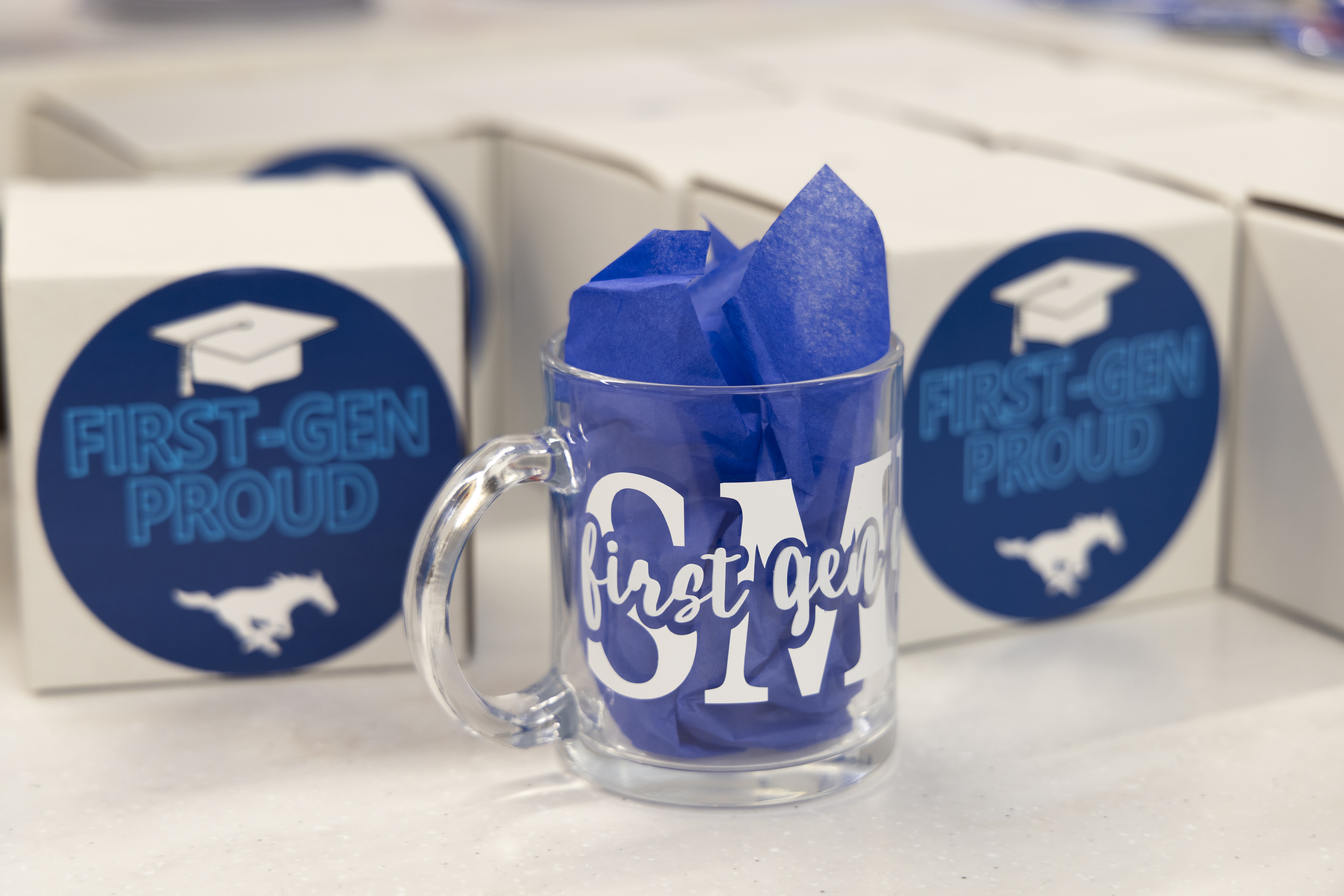Cups with SMU First--Gen lettering, boxes with first gen proud stickers in the background
