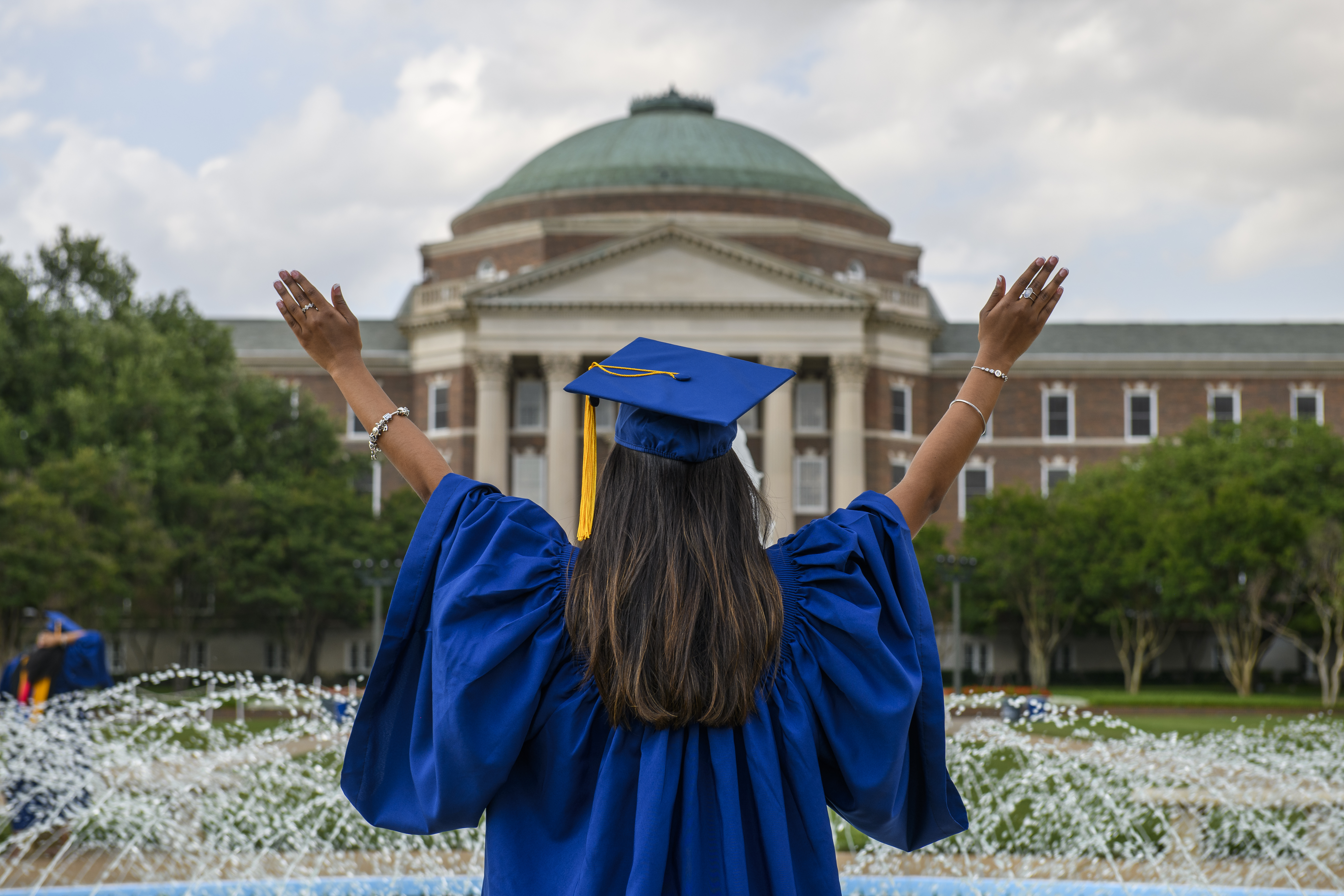 graduate in front of Dallas Hall