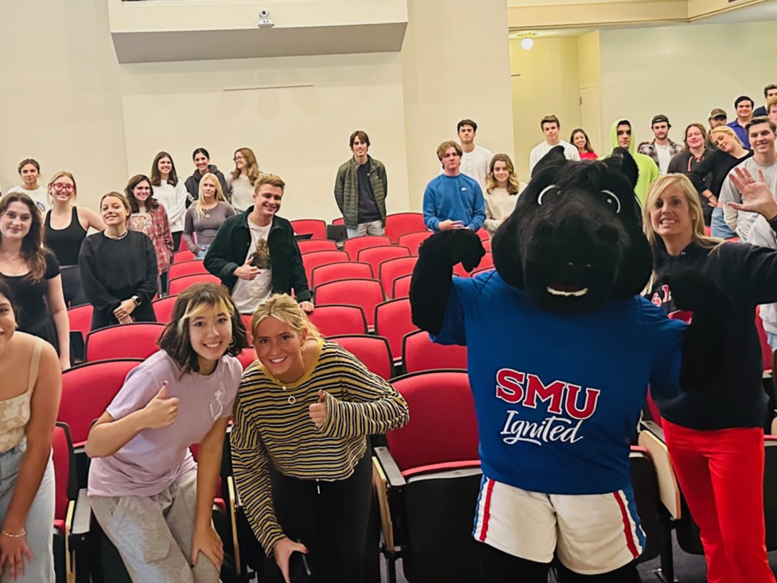 SMU students gathered in a lecture hall with the SMU mascot during a campus event.