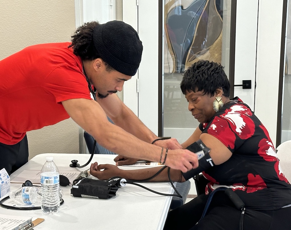 A Simmons Applied Physiology and Health Management student works with a patient at a community health event.