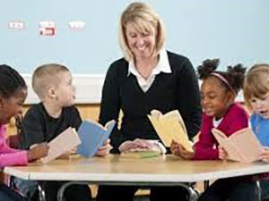 Teacher sitting at table with four young students
