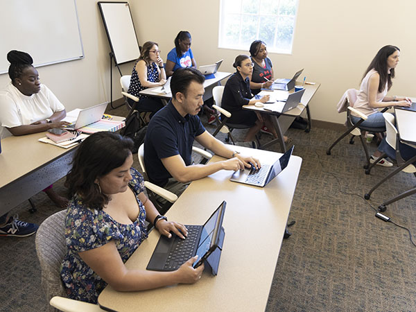 Adult learners using laptops in an SMU classroom