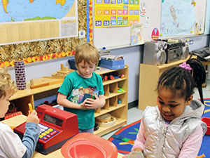 A group of kindergarten children play together in a colorful classroom filled with educational materials and toys