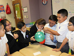 A group of children in a classroom holding colorful balloons during an activity.