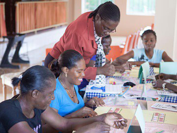 A group of women engaged in activities at a table, fostering community and learning in Jamaica's Parent Math Training Pilot.