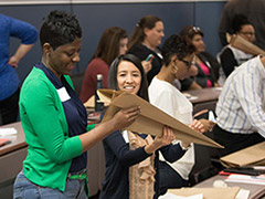 A diverse group of people engaged in a classroom activity using paper and scissors for a creative project.