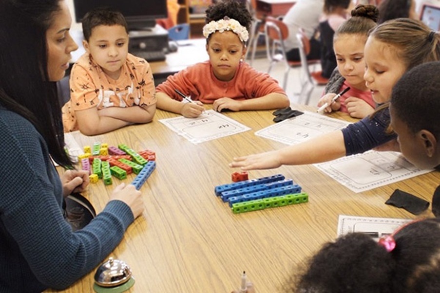 Teacher working with middle school students using fraction manipulatives.