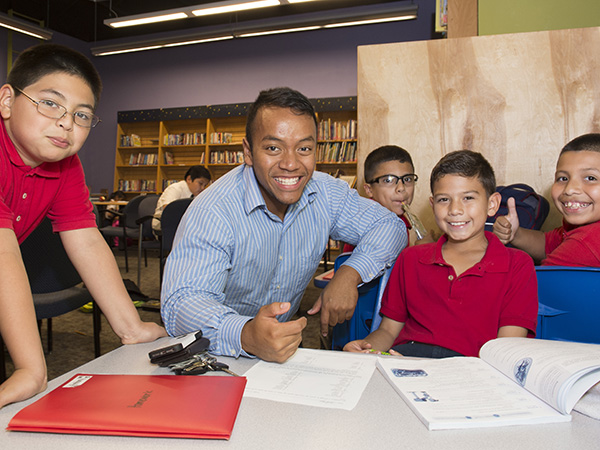 Middles school teacher sitting with group of kids doing math work.