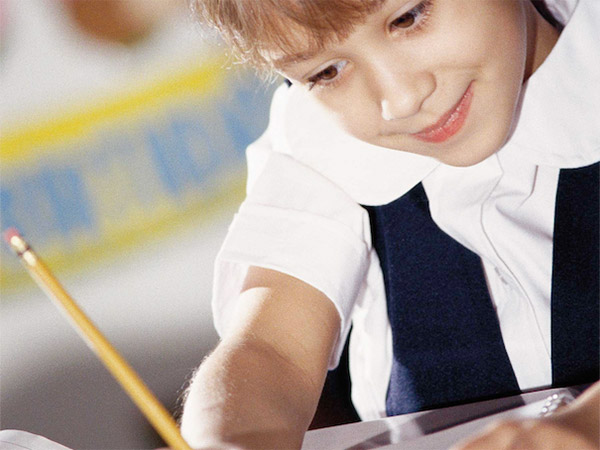 A young girl is focused on writing on a piece of paper.