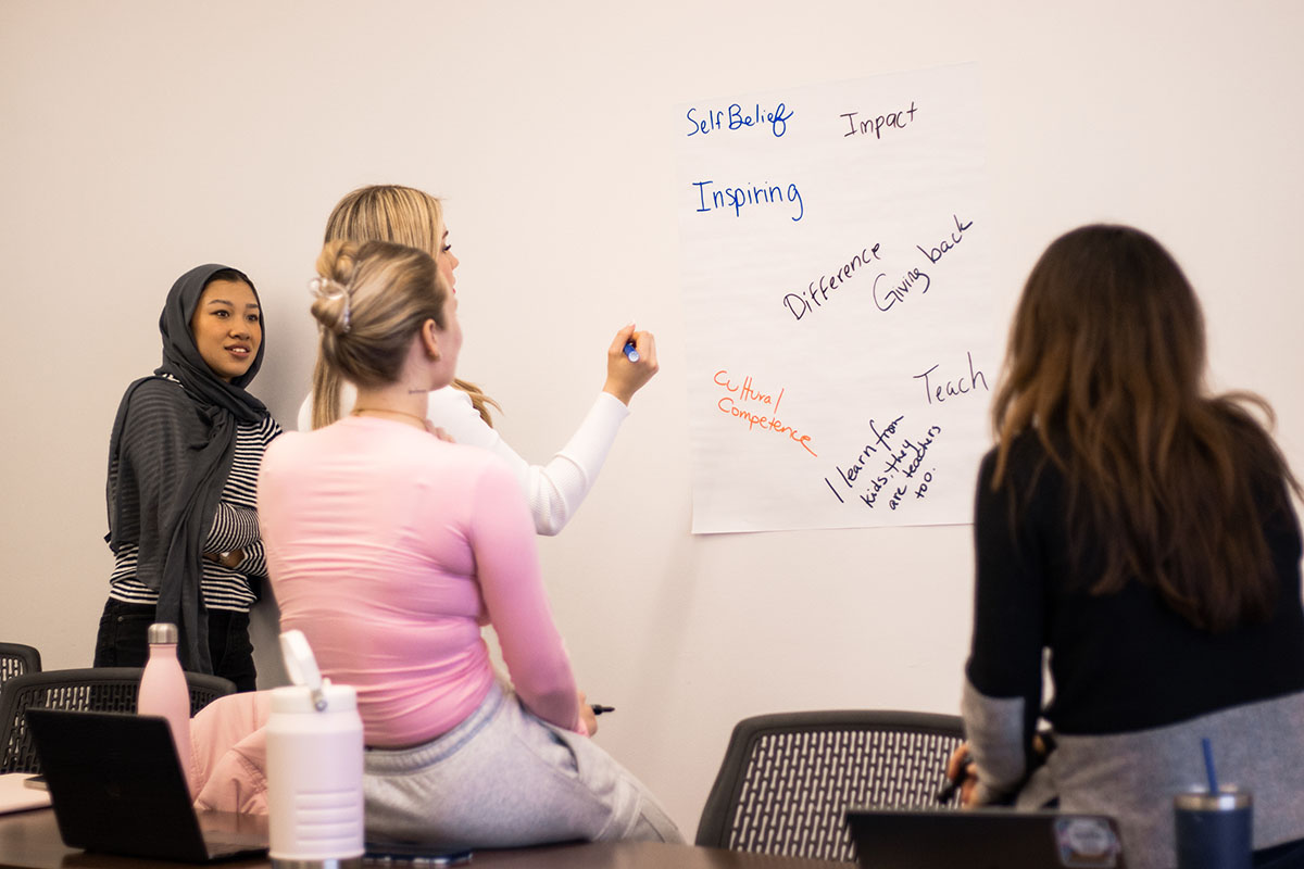 Teacher prepartation course. Students working together on whiteboard.