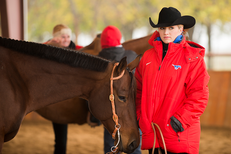 Equestrian athlete standing next to a horse
