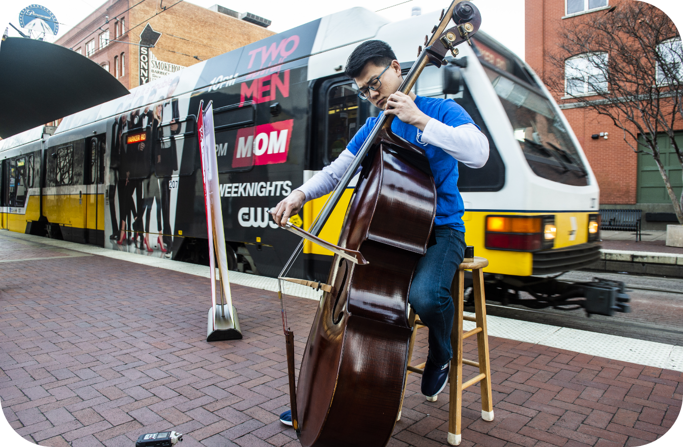 Student playing the cello at a DART train station