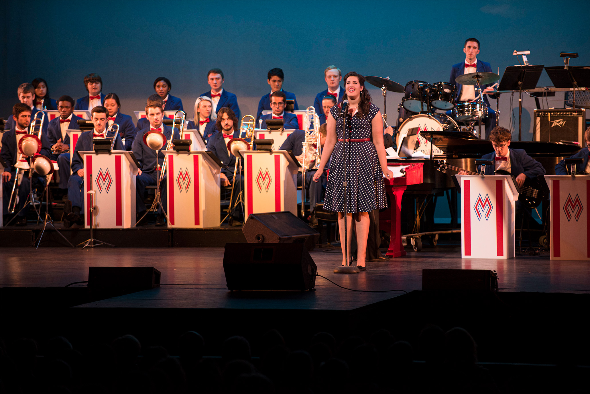 student sining in front of band at pigskin revue