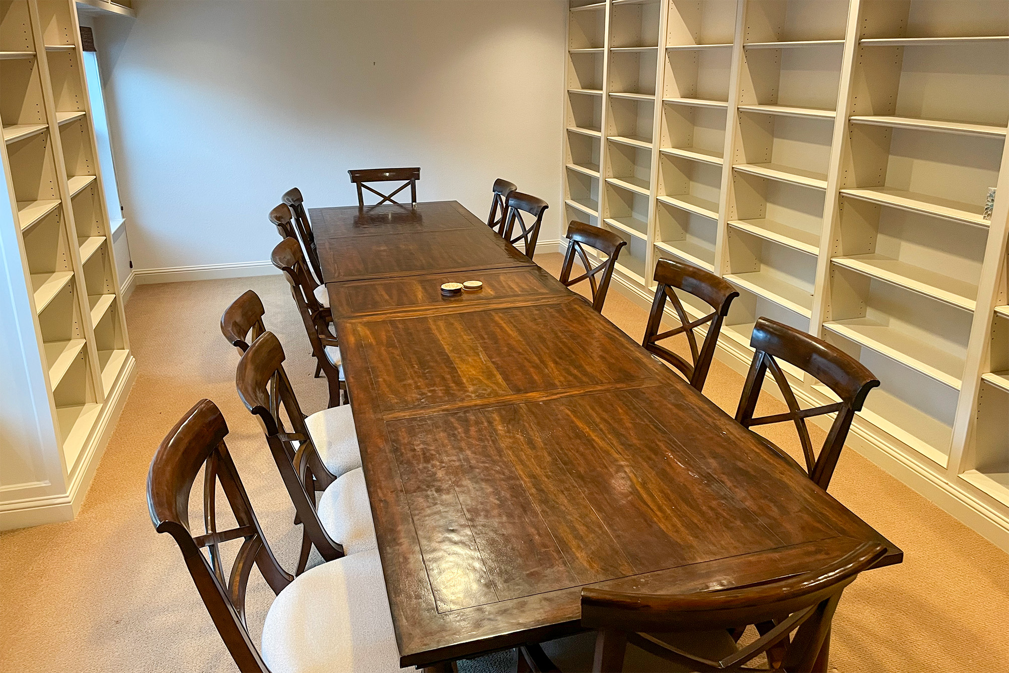 interior room with light colored walls and built in bookshelves lining the perimeter of the room, long dark wood table with 12 chairs in the middle of room