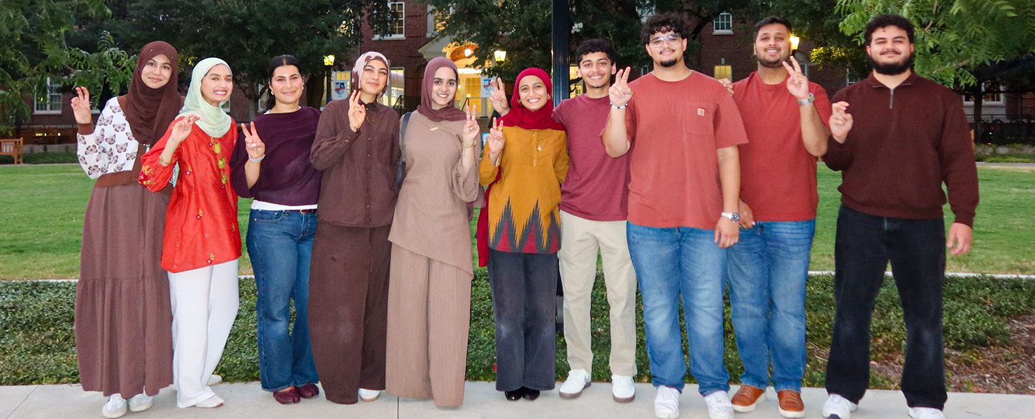 group of people standing outside posing for photo with pony up hand sign