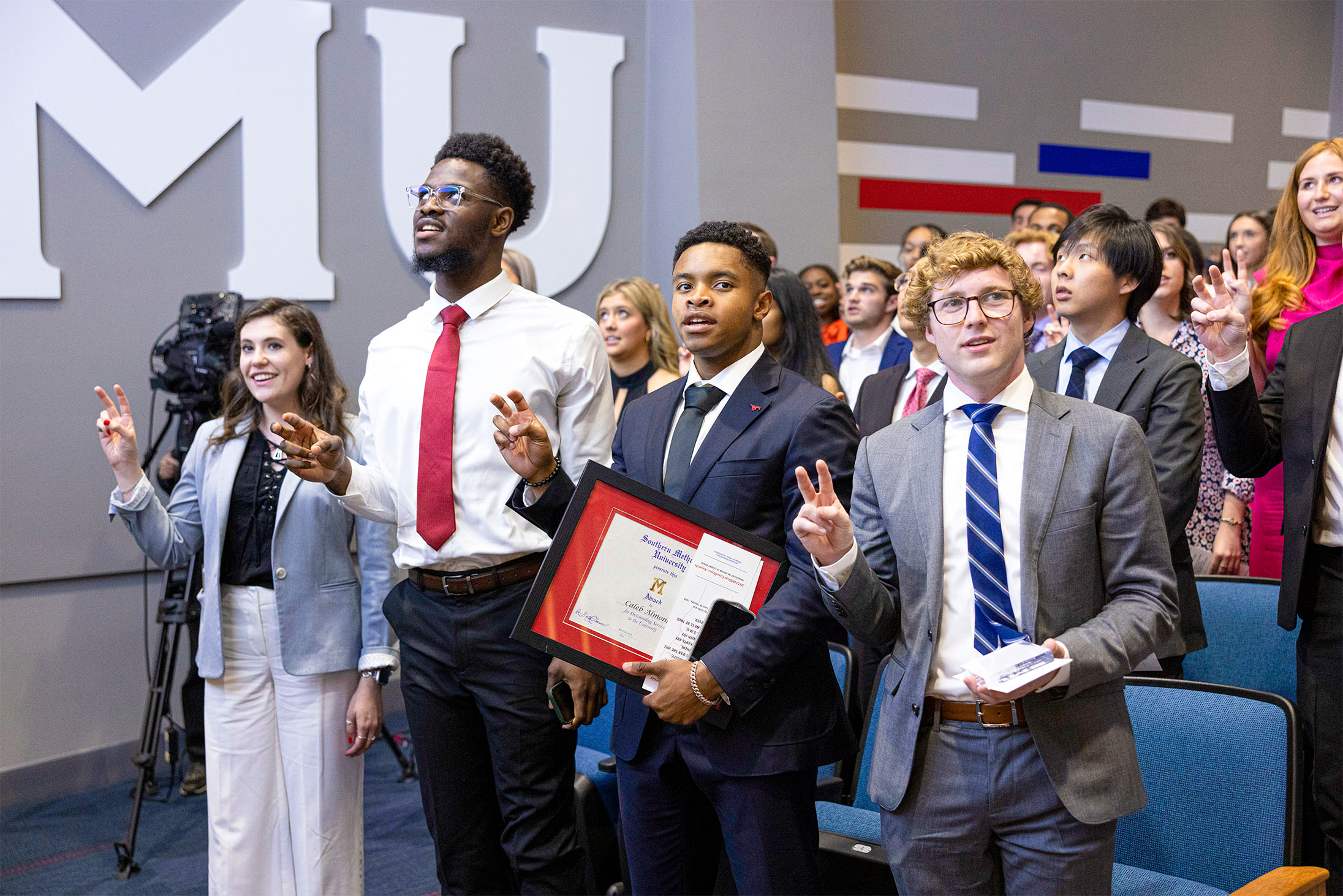 students standing holding pony up hand signal 