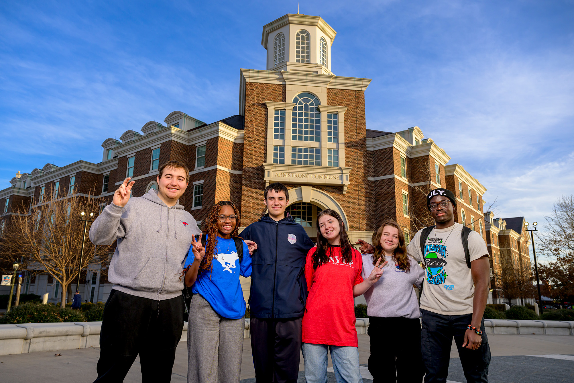 group of students posing for photo outside of brick building