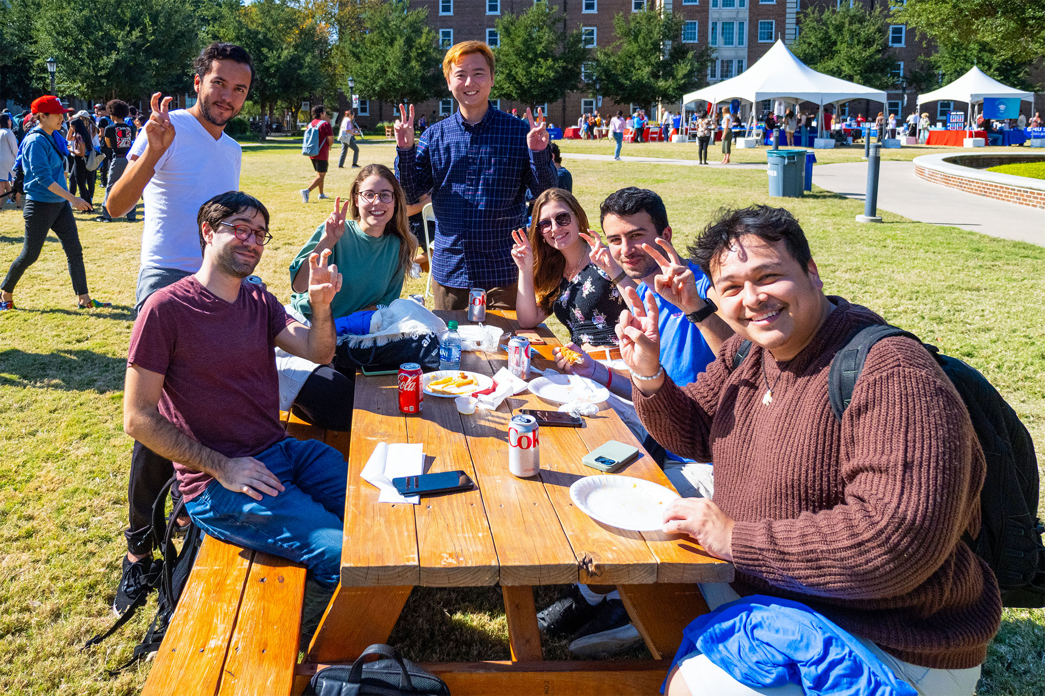 Students sitting at picnic table on MHPS lawn holding Pony Up hand sign