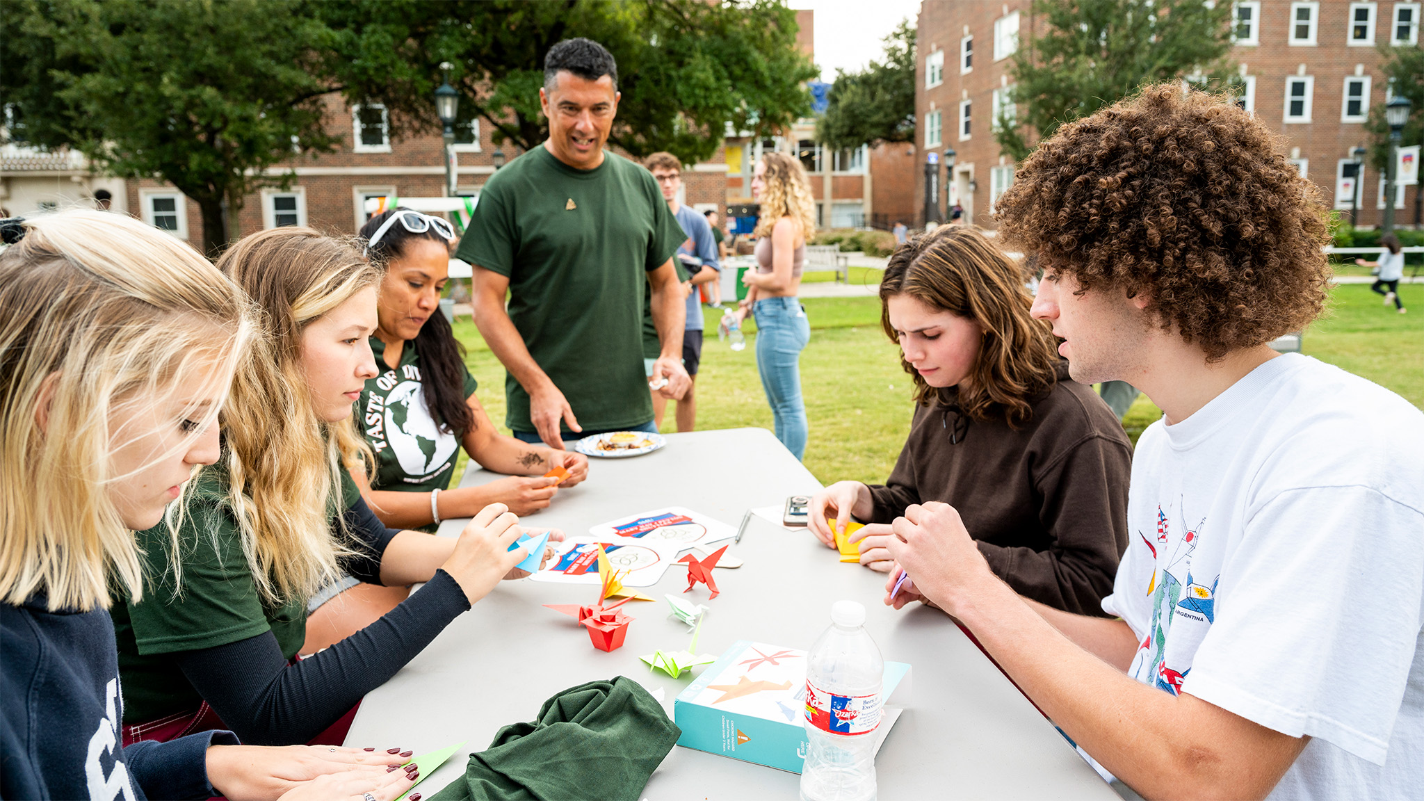 Dr. Alberto Pastor with students outside making crafts at table