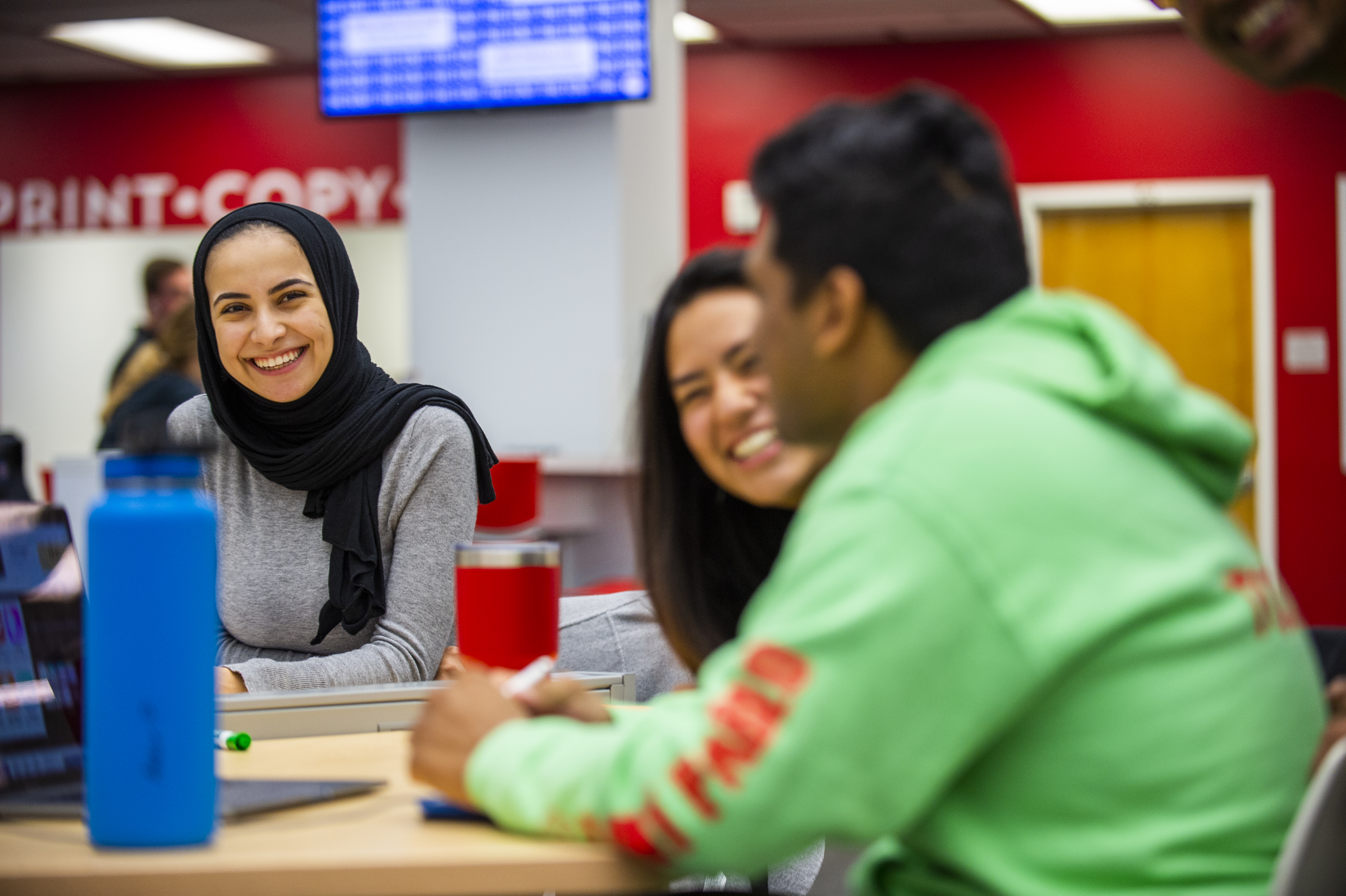 Three students smiling in the library
