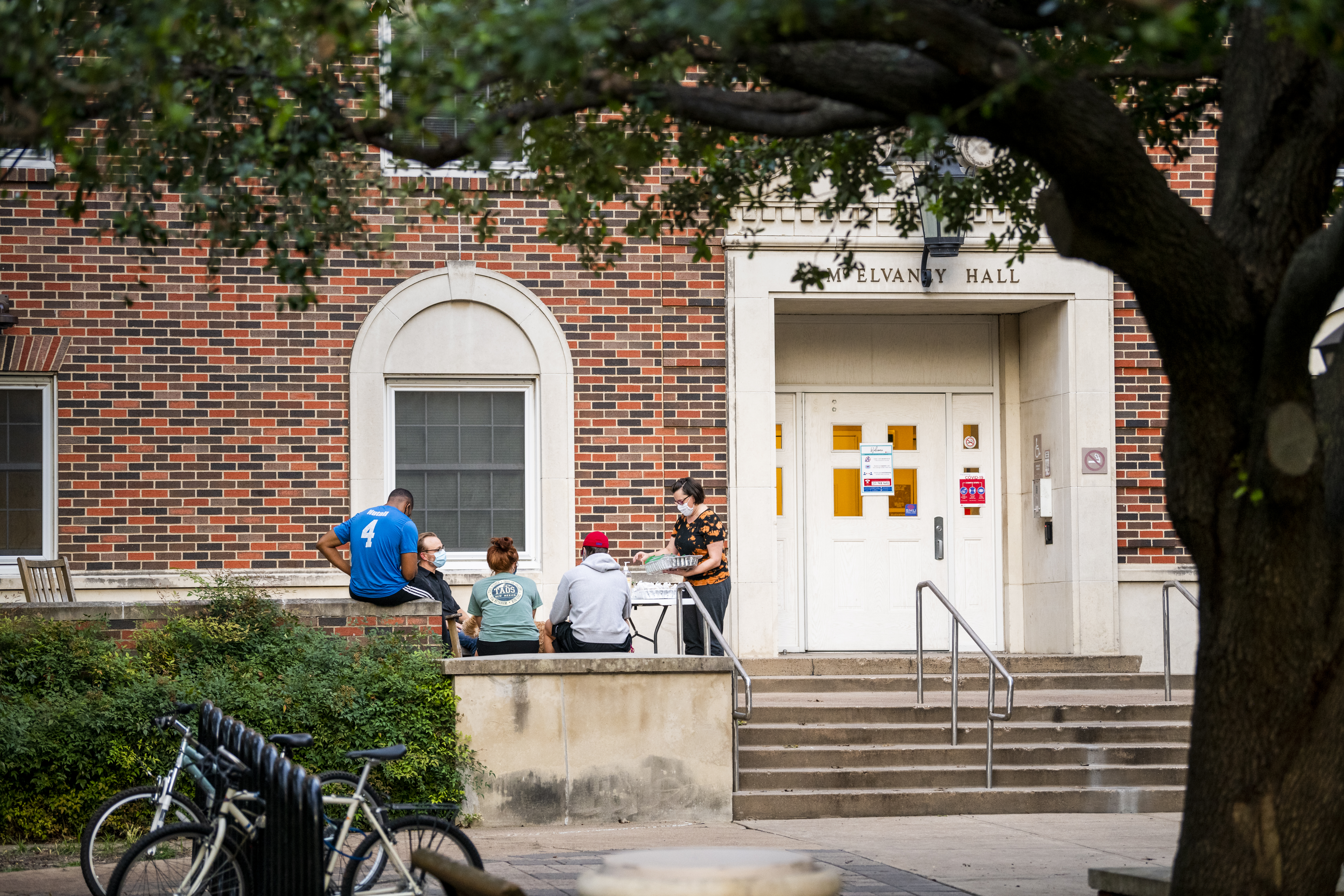 Exterior of McElvaney Residential Commons, with students sitting outside