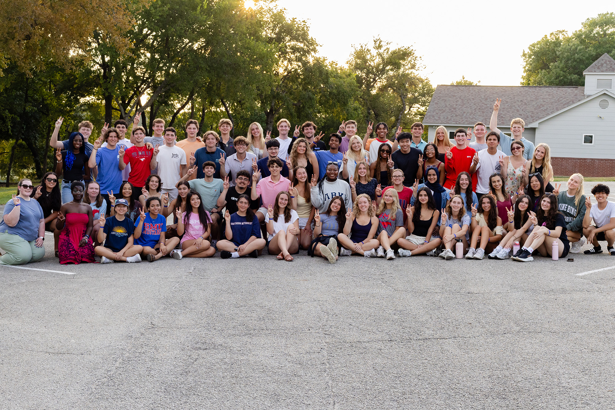 large group of people posing for photo outside with green trees in the background