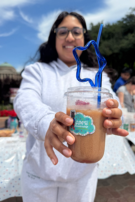 person in background holding drink in focus of the camera standing outside