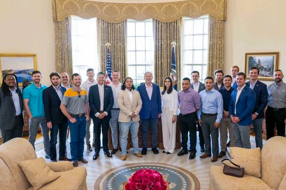 military veteran students posing for photo with former President George W. Bush
