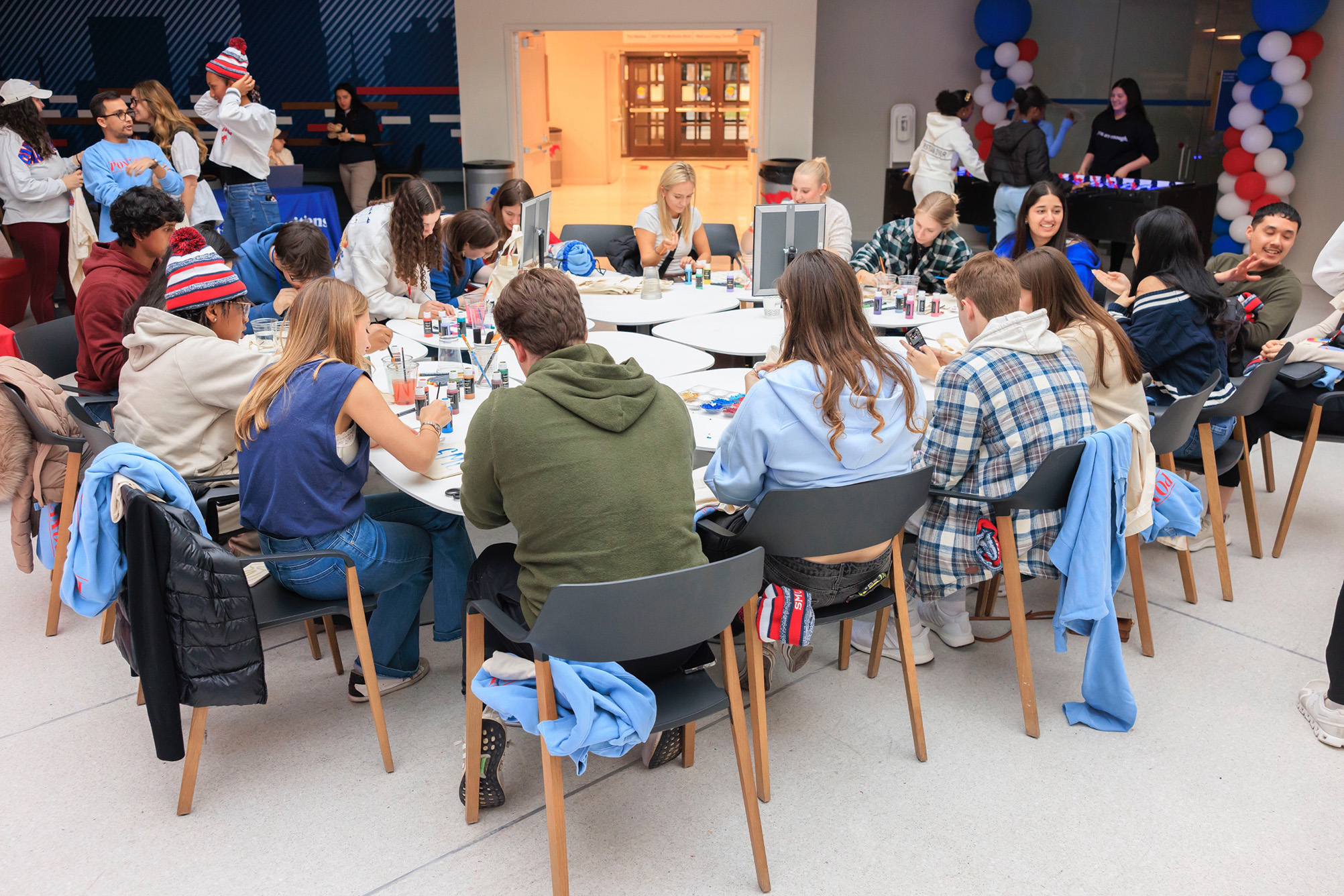 large group of students sitting at tables painting