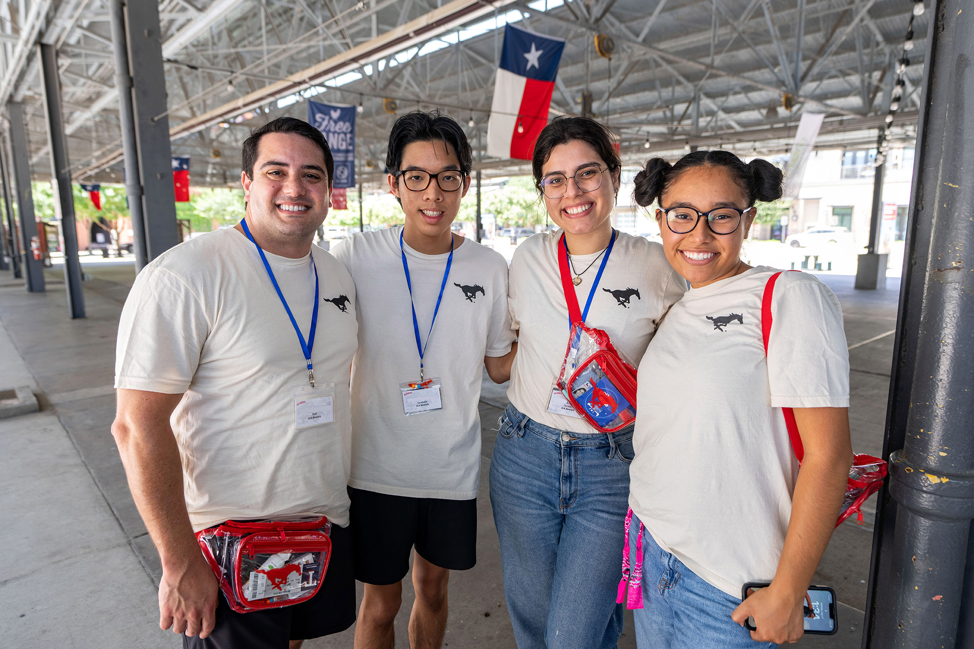 four people standing outside under stadium seats posing for a photo